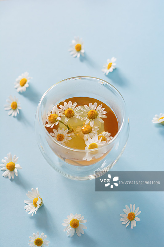 蓝色背景上的洋甘菊茶。舒缓的草本茶对身体有益。图片素材