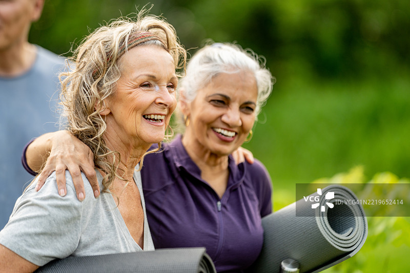 两位年长女性在户外微笑，刚刚结束放松的瑜伽课程图片素材
