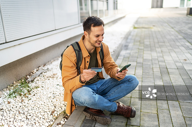 年轻游客使用手机在线刷信用卡付款图片素材