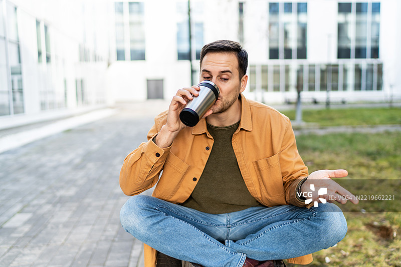年轻男子在城市环境中享受户外咖啡休息时间图片素材