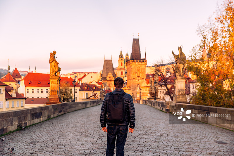 秋季，捷克共和国布拉格查尔斯桥上的男子背影图片素材