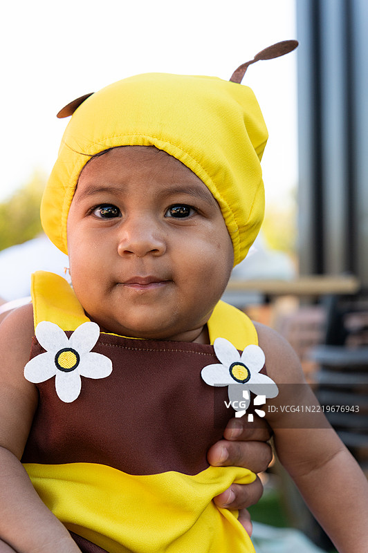 可爱的婴儿穿着蜜蜂服装，正看着镜头。图片素材