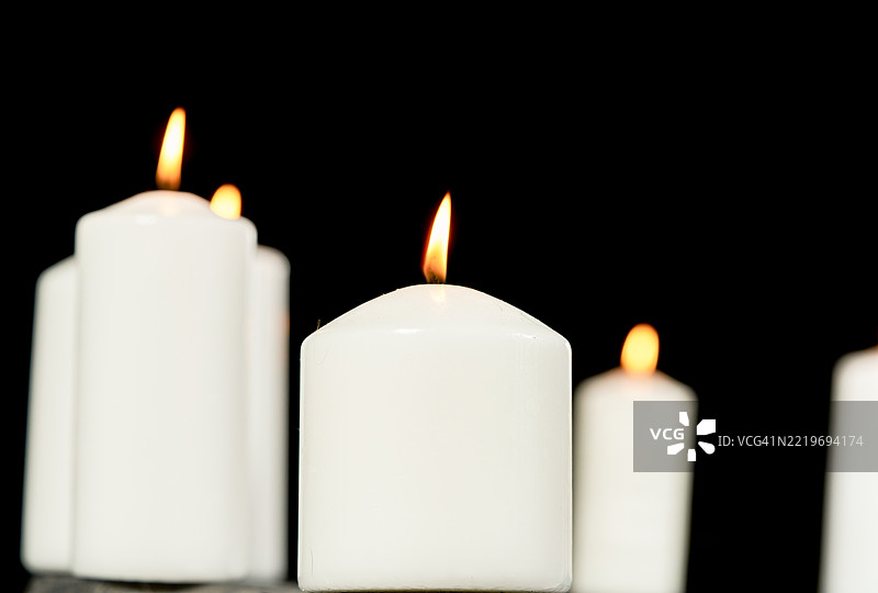 黑色背景上的燃烧白色蜡烛营造出温暖的氛围图片素材