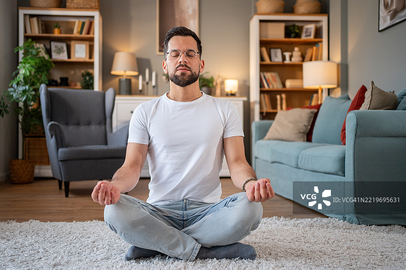 年轻男子在家中的客厅冥想图片素材
