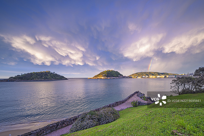 雨后光辉洒在拉孔查海滩上，彩虹拱桥横跨天际图片素材