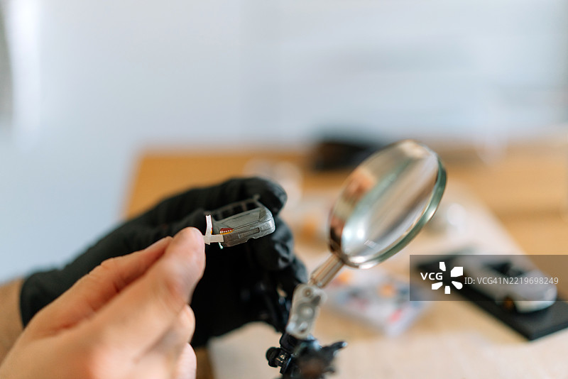 在家中，某人手持放大镜的特写手部图片素材