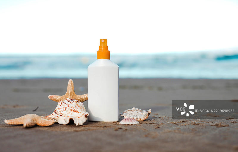 沙滩上有贝壳的防晒霜瓶图片素材