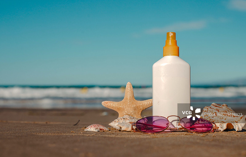 沙滩必备品：防晒霜、太阳镜、海星和沙滩贝壳在沙滩上图片素材