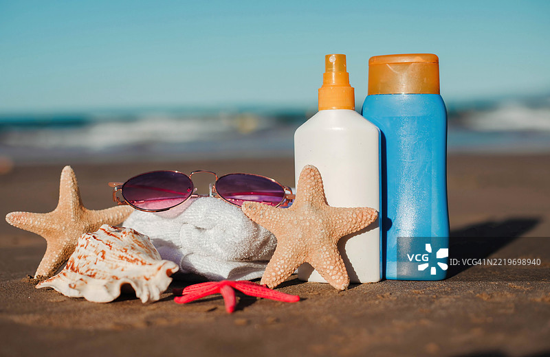 夏季海滩必备品，沙滩上的防晒霜和海星图片素材