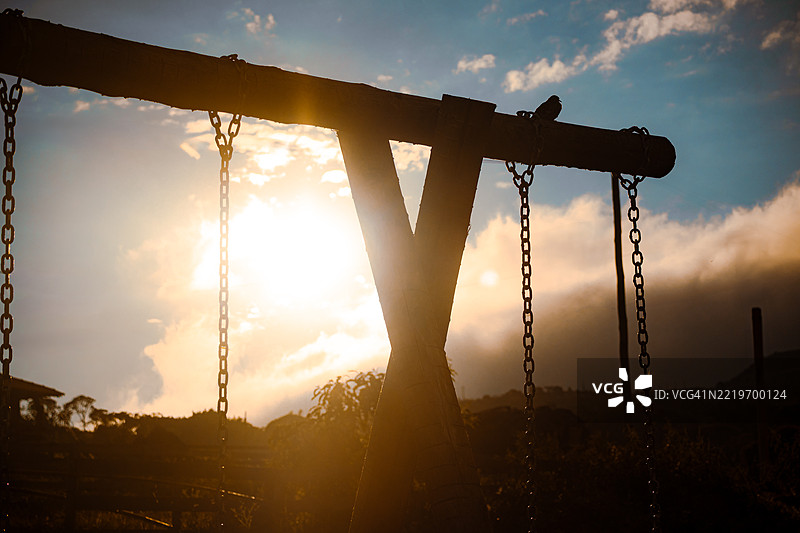 日落时分，低角度视图下秋千的剪影与天空相映成趣图片素材