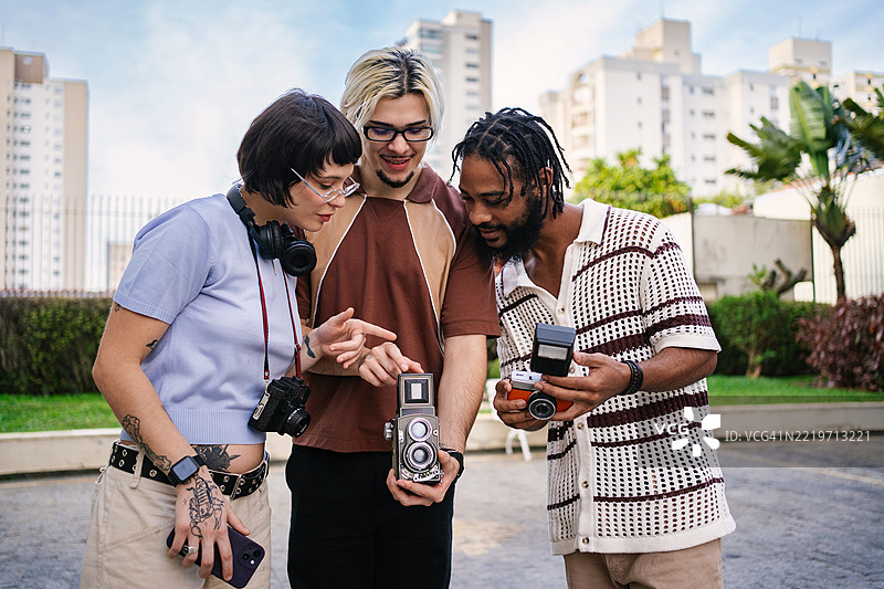 一群年轻朋友在使用老式胶卷相机互动图片素材