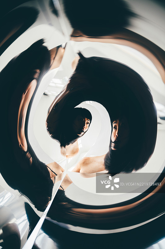 一位亚洲女性在可调镜子前观察自己。图片素材