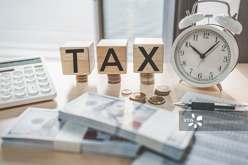 税务概念，木块上写有税务字样，旁边堆放着硬币图片素材