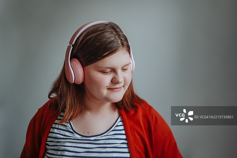 闭眼的青少年特写，戴着大耳机，背景为白色墙壁。图片素材