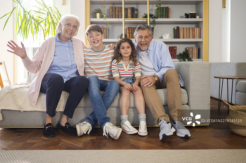 多代家庭肖像：快乐的祖父母和孙子孙女坐在沙发上图片素材