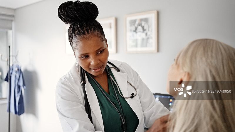 医生在诊所为一位年长女性患者进行检查图片素材