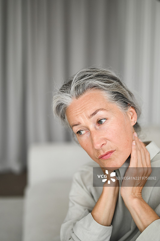 在家中遭受颈部疼痛的成熟的女性图片素材