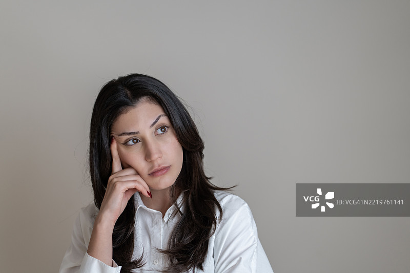 年轻女性在白色背景前露出思考的表情图片素材