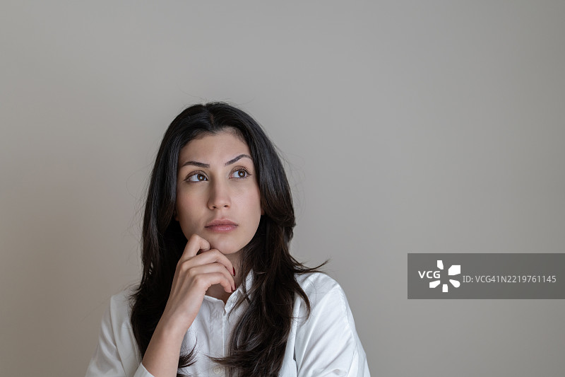 年轻女性在白色背景下思考的表情图片素材