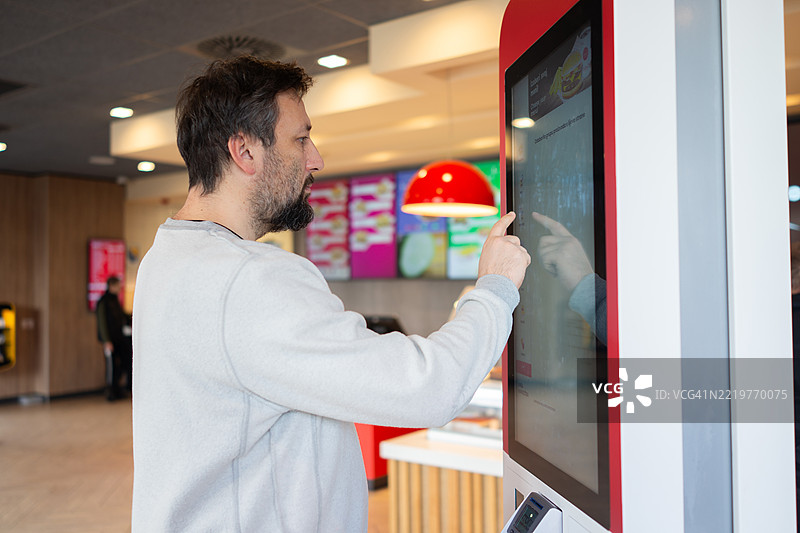 男子在餐厅的触摸屏上点快餐图片素材