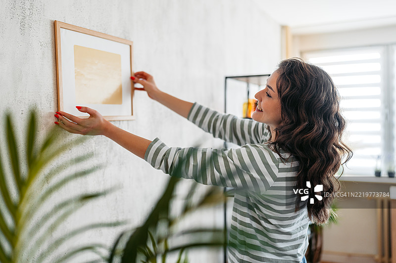 年轻女性在墙上挂画图片素材