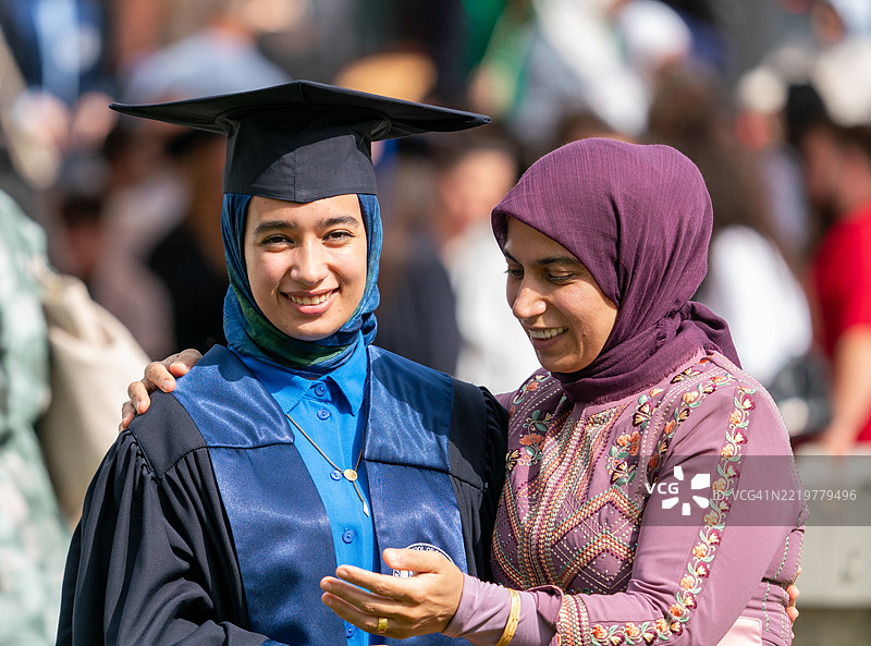 年轻的戴头巾女性与母亲庆祝毕业，母爱的温暖图片素材