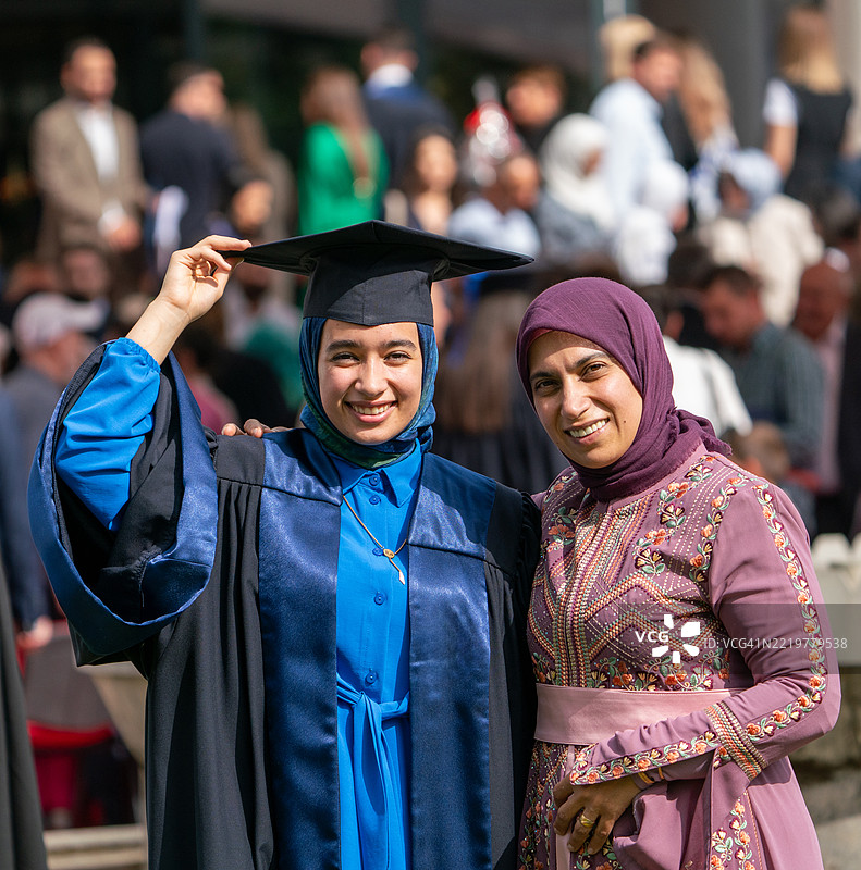 年轻的戴头巾女性与母亲庆祝毕业，母爱的温暖图片素材