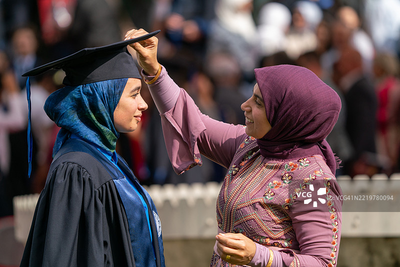 年轻的戴头巾女性与母亲庆祝毕业，母爱的温暖图片素材