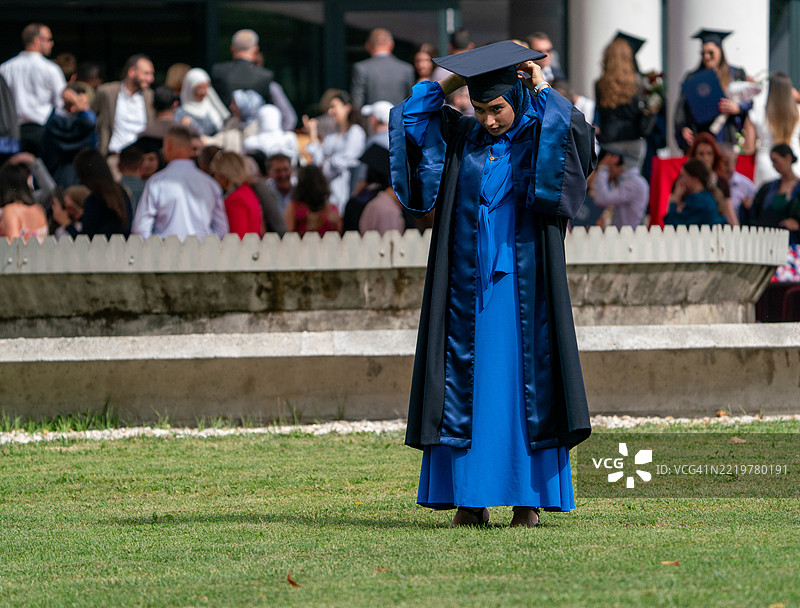 穆斯林女毕业生在人群中脱颖而出，随意地将帽子抛向空中图片素材