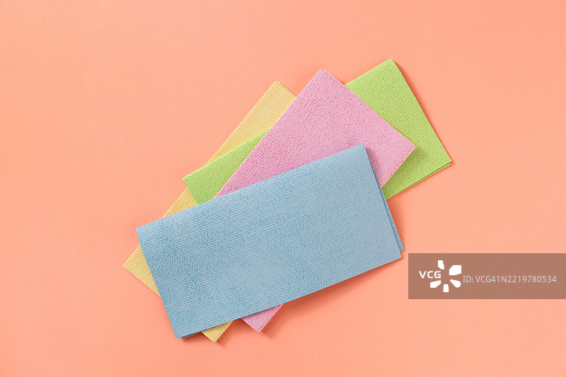 五颜六色的清洁布叠放在淡橙色背景上图片素材
