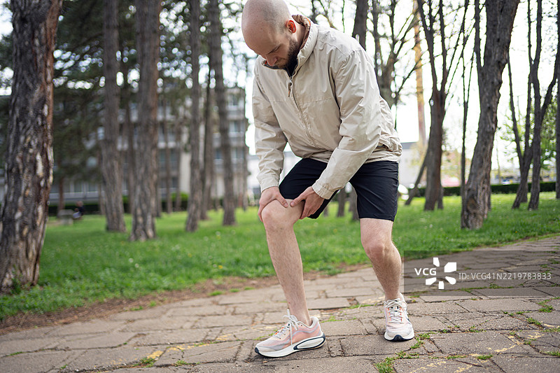 年轻男子在户外训练，停在公园里拉伸和恢复。图片素材