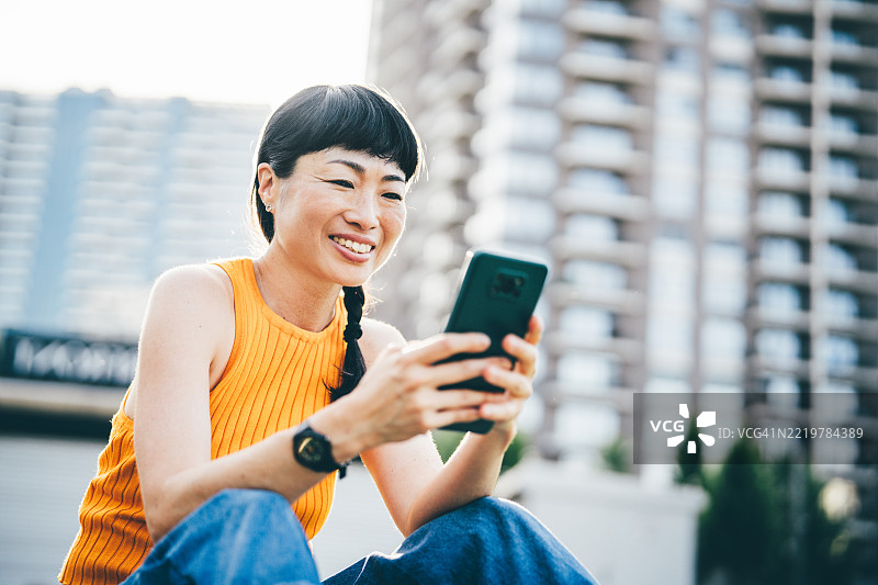 女性在城市公园使用智能手机。图片素材