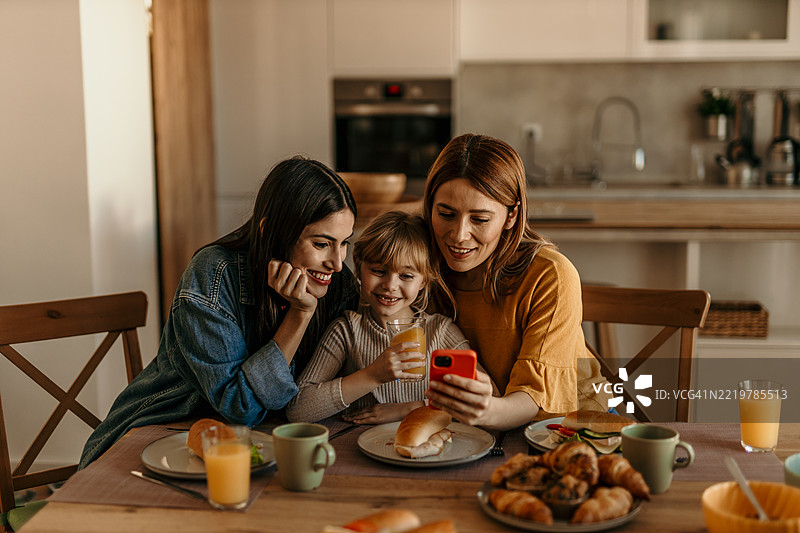 一家人在家一起吃早餐并使用智能手机图片素材