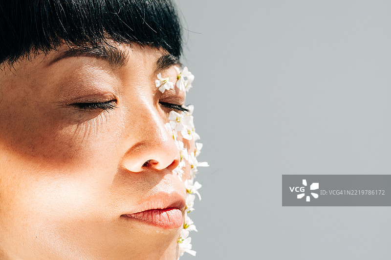 美丽的亚洲女性脸上贴着花朵，美容与护肤概念。图片素材