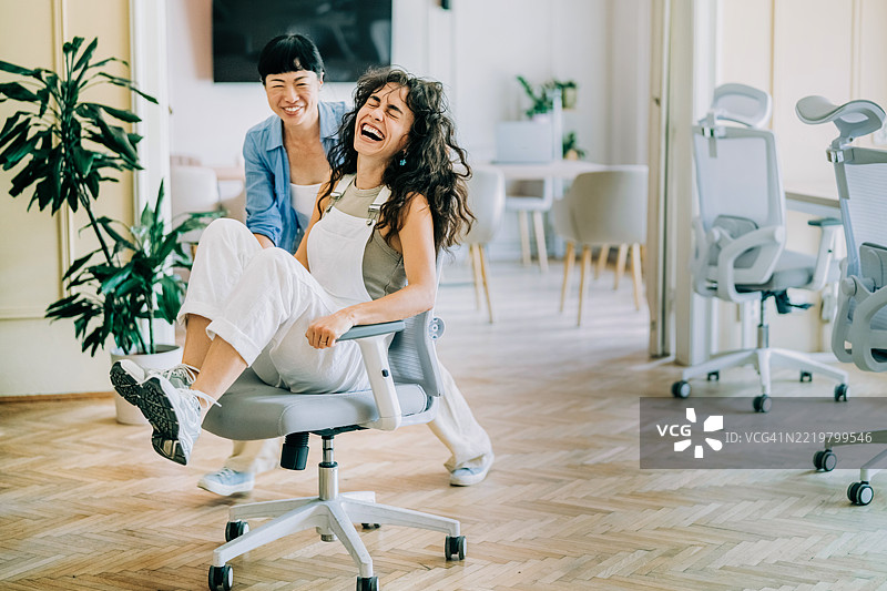 办公室椅子比赛。同事们在办公室里玩得很开心。图片素材