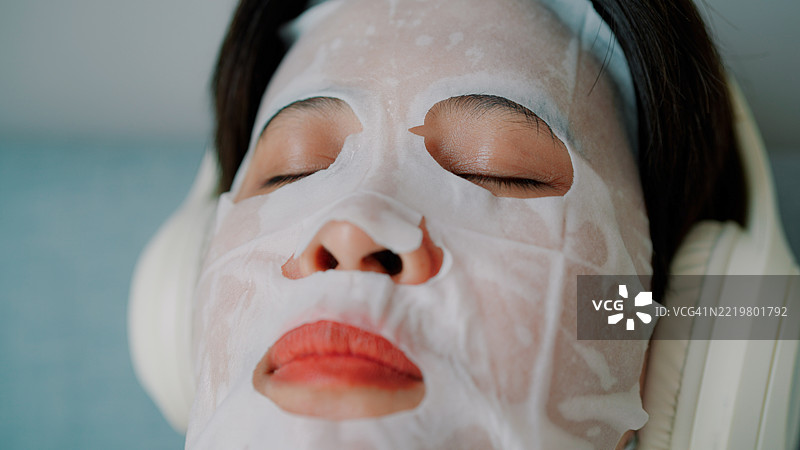 亚洲女性在家中戴着面膜听音乐图片素材