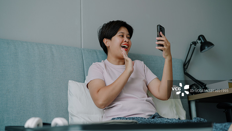 亚洲女性在卧室使用智能手机图片素材