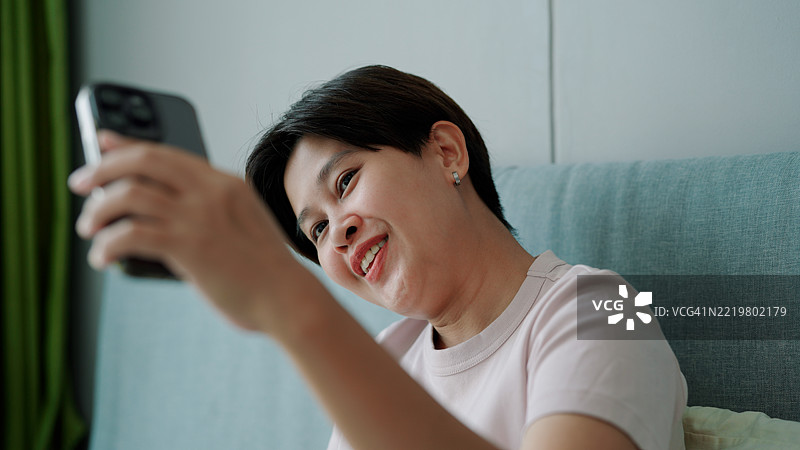 亚洲女性在卧室使用智能手机图片素材