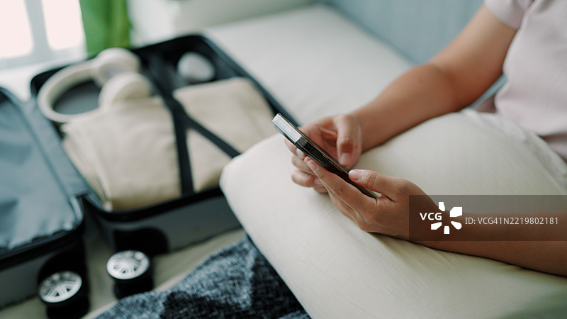 亚洲女性正在使用手机并准备行李旅行图片素材