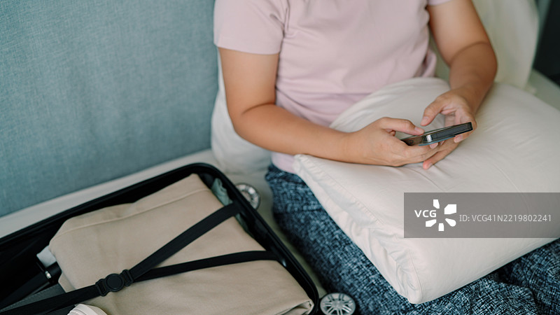 亚洲女性正在使用手机并准备行李旅行图片素材