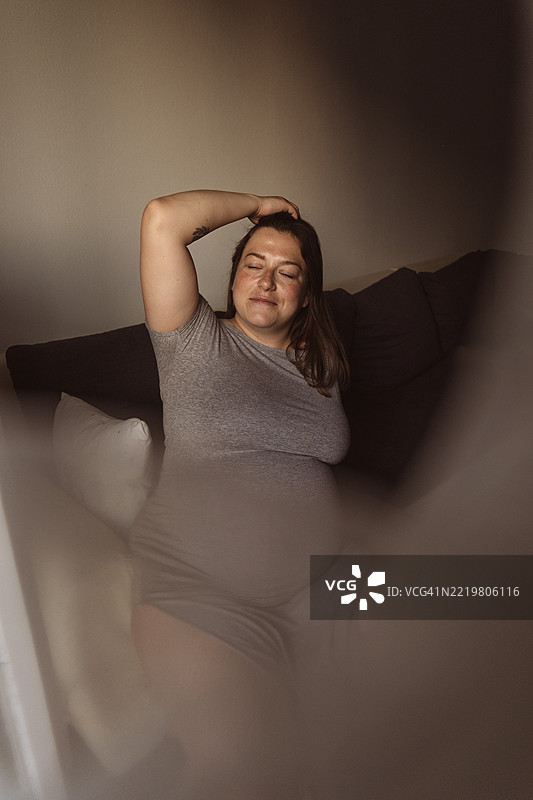 年轻的孕妇在客厅里享受时光图片素材