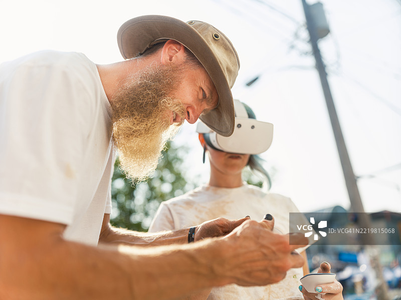 戴着虚拟现实眼镜的年轻女性在城市建筑的外立面上创作壁画图片素材