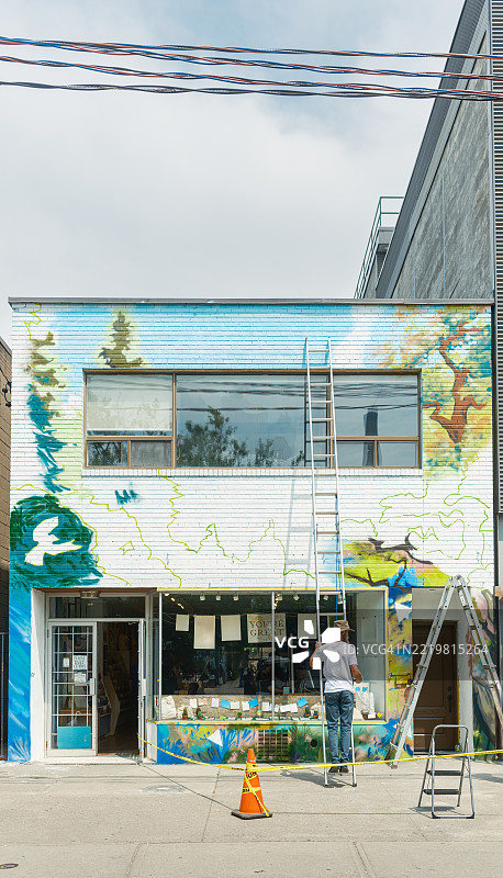年轻人在城市建筑的外立面上创作壁画图片素材
