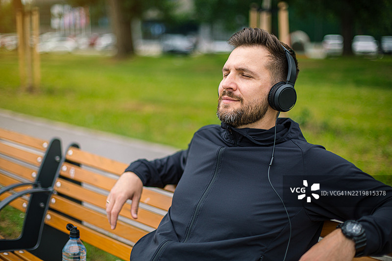 运动员在长椅上放松，听音乐，锻炼后休息。图片素材