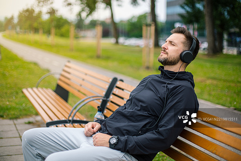 运动员在长椅上放松，听音乐，锻炼后休息。图片素材