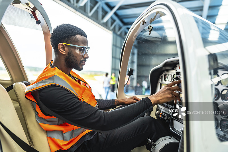 飞机工程师仔细检查小型飞机驾驶舱内的仪器和控制装置，确保飞行前的安全和最佳性能。图片素材