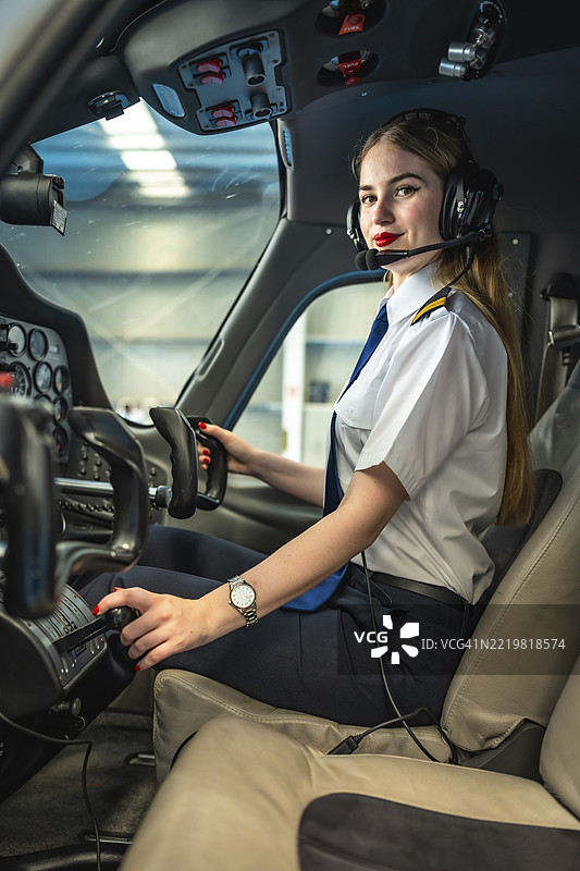 自信的女性飞行员坐在小型飞机的驾驶舱内，调整控制装置，准备起飞。图片素材