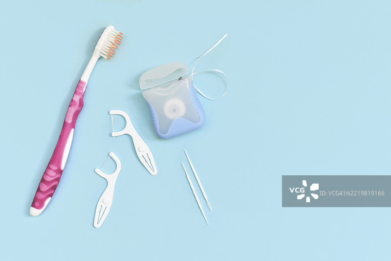蓝色背景旁边的牙线、牙签和牙刷，留有空白空间图片素材