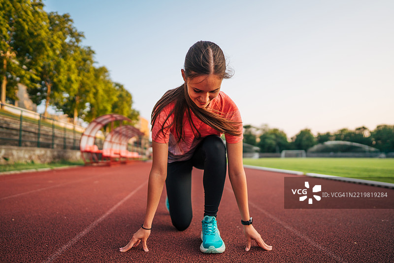 年轻女运动员在跑道上准备跑步图片素材