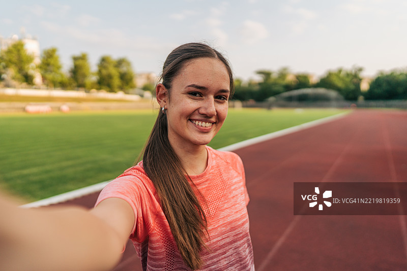 年轻的运动女性在跑道上自拍图片素材